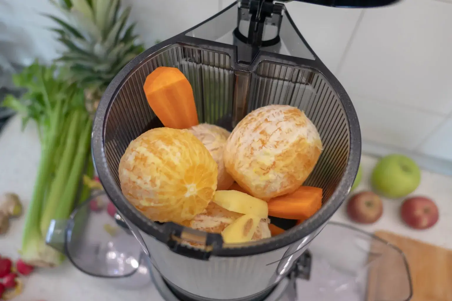 Korenje, ingver in pomaranča v posodi počasnega sokovnika